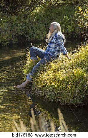 Stock Photo - Caucasian woman dipping feet in river. Fotosearch