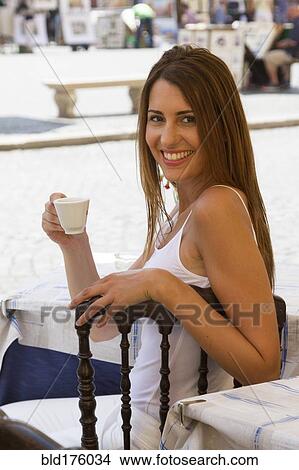 Picture - Caucasian woman drinking coffee outdoors. Fotosearch