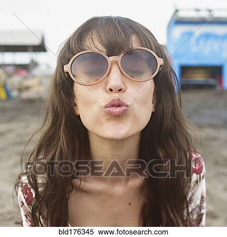 Stock Photography - Caucasian woman in sunglasses puckering to kiss at beach. Fotosearch