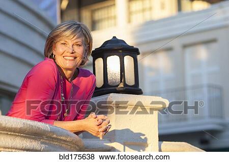 Stock Photo - Caucasian woman leaning over balcony. Fotosearch
