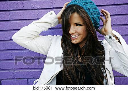 Stock Image - Caucasian woman near purple brick wall. Fotosearch