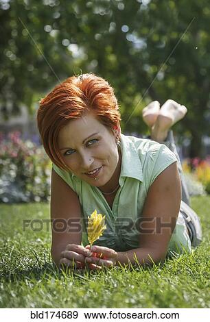 Stock Photo - Caucasian woman smiling in grass. Fotosearch