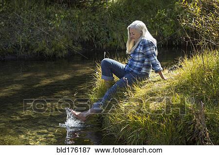 Stock Photo - Caucasian woman splashing feet in river. Fotosearch