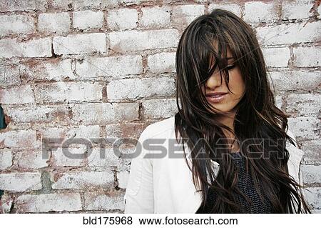 Stock Photo - Caucasian woman standing at brick wall. Fotosearch