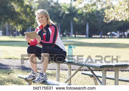 Caucasian woman using digital tablet in park View Large Photo Image Stock Image - Caucasian woman using digital tablet in park. Fotosearch