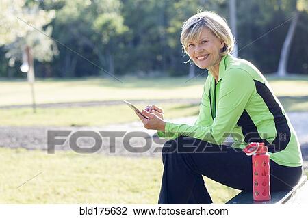 Stock Image - Caucasian woman using digital tablet in park. Fotosearch