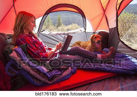 Stock Image - Caucasian woman using digital tablet in camping tent. Fotosearch