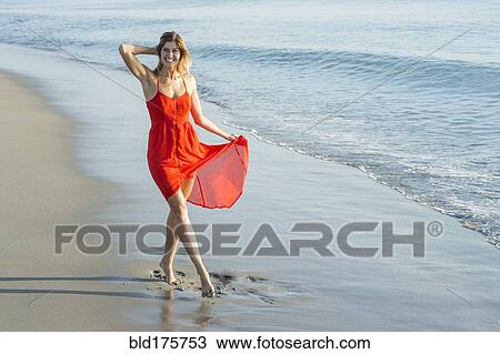 Stock Image - Caucasian woman walking on beach. Fotosearch