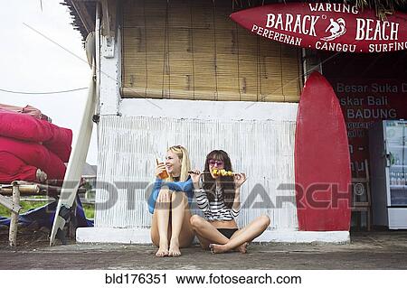 Stock Image - Caucasian women eating at surf hut on beach. Fotosearch