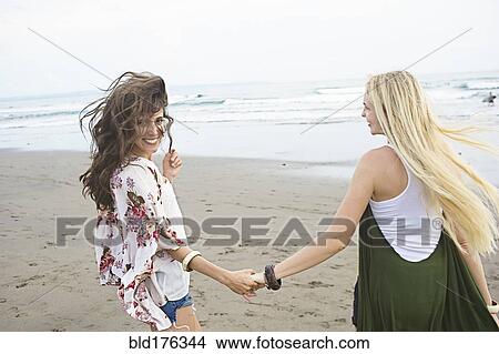 Caucasian women holding hands on beach View Large Photo Image Picture - Caucasian women holding hands on beach. Fotosearch