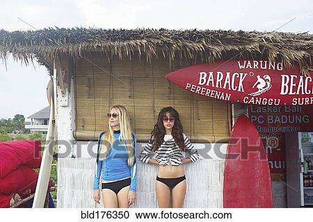 Stock Image - Caucasian women standing at surf hut on beach. Fotosearch