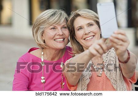 Stock Image - Caucasian women taking selfie with cell phone. Fotosearch