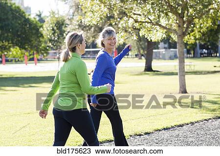 Stock Image - Caucasian women walking in park. Fotosearch