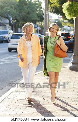Picture - Caucasian women walking on city sidewalk. Fotosearch