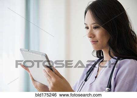 Stock Photograph - Chinese nurse using digital tablet. Fotosearch