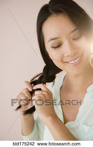 Stock Image - Chinese woman braiding her hair. Fotosearch