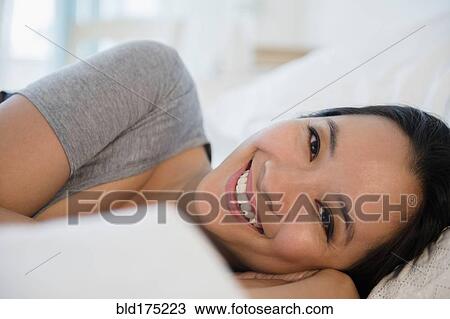 Stock Image - Chinese woman laying on bed. Fotosearch