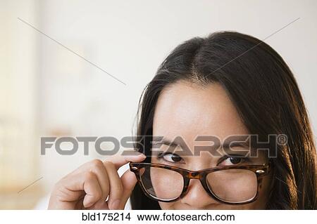 Picture - Chinese woman peering over eyeglasses. Fotosearch