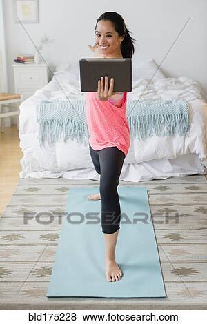 Stock Photo - Chinese woman practicing yoga with digital tablet. Fotosearch