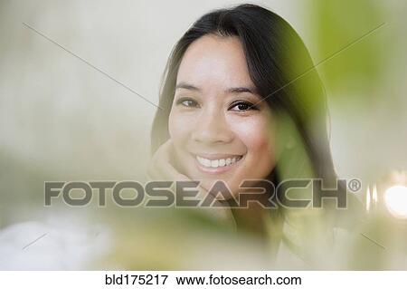 Stock Photo - Chinese woman smiling with chin in hand. Fotosearch
