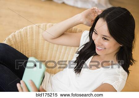 Stock Photography - Chinese woman taking selfie with cell phone. Fotosearch
