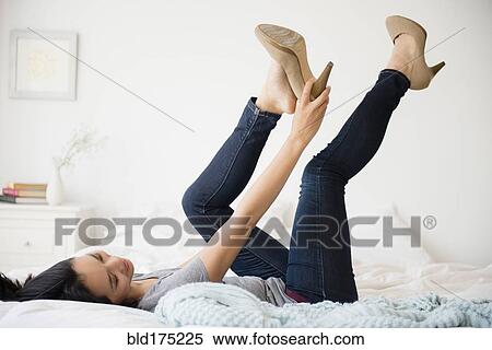 Stock Photography - Chinese woman trying on shoes on bed. Fotosearch