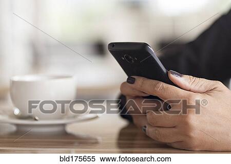 Stock Photography - Close up of mixed race woman using cell phone in cafe. Fotosearch