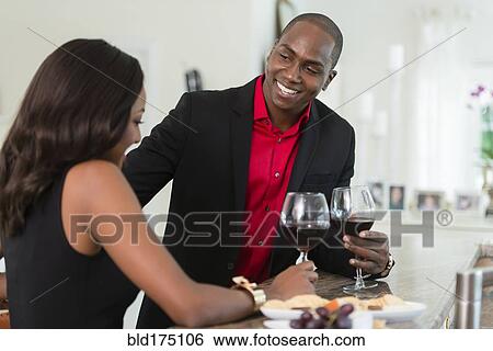Stock Photograph - Couple drinking wine at counter. Fotosearch
