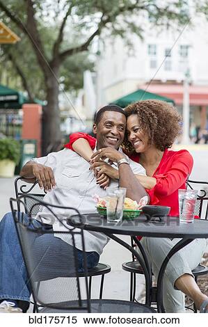 Stock Photography - Couple hugging at outdoor restaurant table. Fotosearch