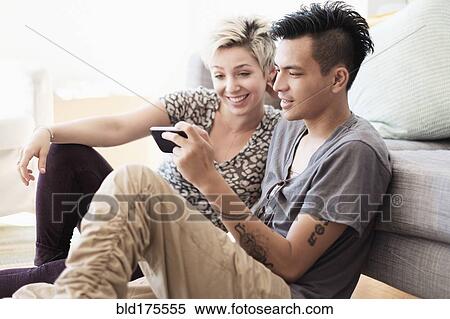 Stock Photography - Couple using cell phone in living room. Fotosearch