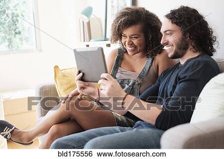 Stock Photograph - Couple using digital tablet on sofa. Fotosearch