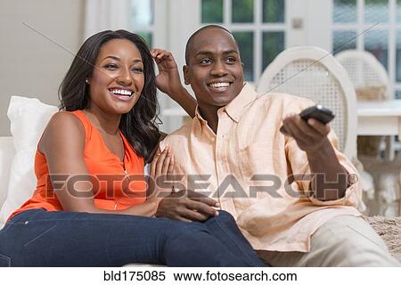 Stock Photography - Couple watching television on sofa. Fotosearch