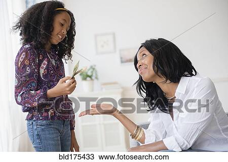 Stock Image - Daughter paying mother in living room. Fotosearch