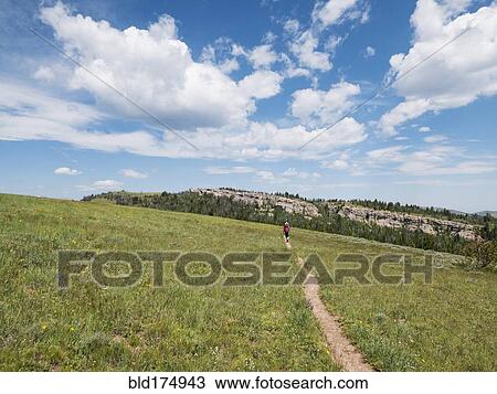 Stock Image - Distant Japanese hiker walking on dirt path. Fotosearch