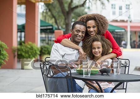 Family smiling at outdoor restaurant table View Large Photo Image Picture - Family smiling at outdoor restaurant table. Fotosearch