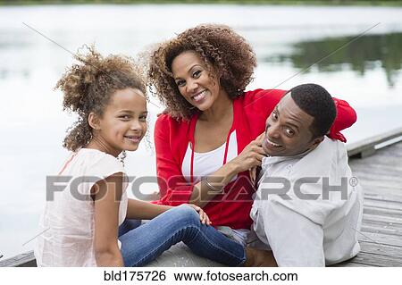 Stock Photograph - Family smiling on wooden dock. Fotosearch