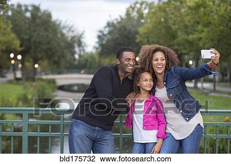 Stock Image - Family taking selfie on bridge. Fotosearch