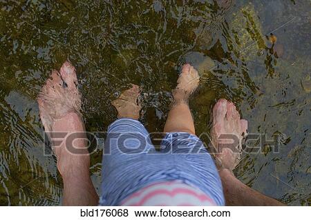 Stock Photo - Father and daughter standing barefoot in water. Fotosearch