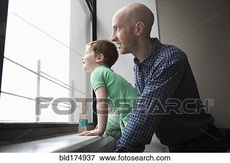 Father and son looking out window View Large Photo Image Stock Photo - Father and son looking out window. Fotosearch