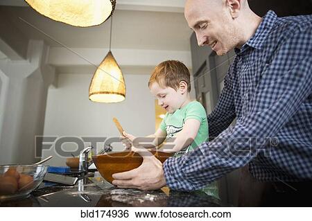 Stock Photograph - Father teaching son to cook in kitchen. Fotosearch