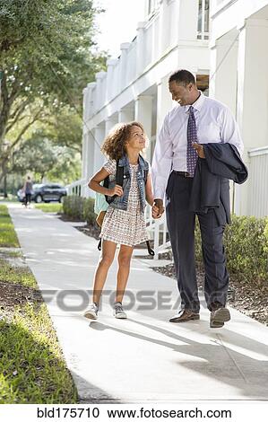 Stock Image - Father walking daughter to school. Fotosearch