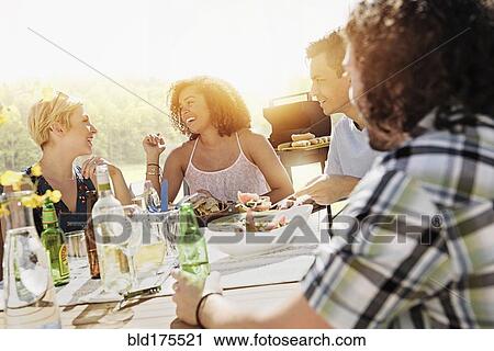 Friends eating together outdoors View Large Photo Image Stock Image - Friends eating together outdoors. Fotosearch