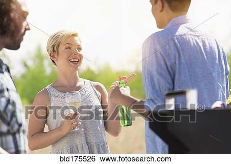 Friends talking at party outdoors View Large Photo Image Stock Photograph - Friends talking at party outdoors. Fotosearch