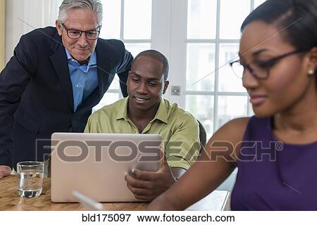 Stock Photo - Friends using laptop at party. Fotosearch