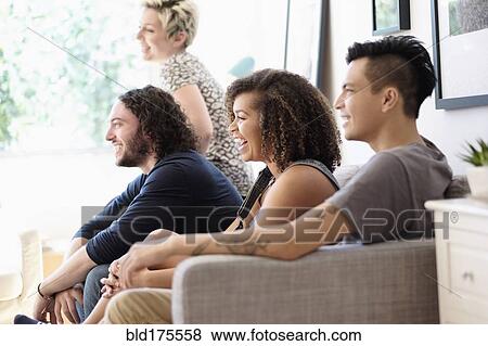 Stock Photo - Friends watching television on sofa. Fotosearch
