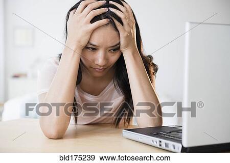 Stock Photo - Frustrated Chinese woman using laptop. Fotosearch