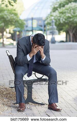 Stock Photo - Frustrated Indian businessman sitting on bench. Fotosearch