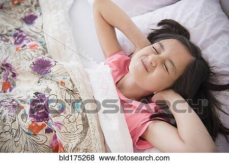 Stock Photo - Girl covering her ears in bed. Fotosearch