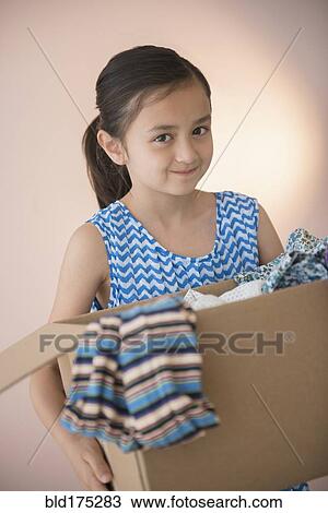 Stock Image - Girl holding box of clothing for donation. Fotosearch
