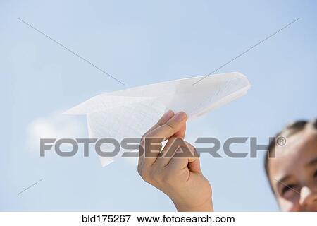 Girl holding paper airplane under blue sky View Large Photo Image Stock Photo - Girl holding paper airplane under blue sky. Fotosearch